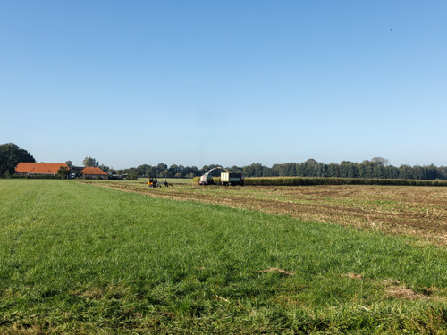 Boerderij in het landschap met een machine op het land