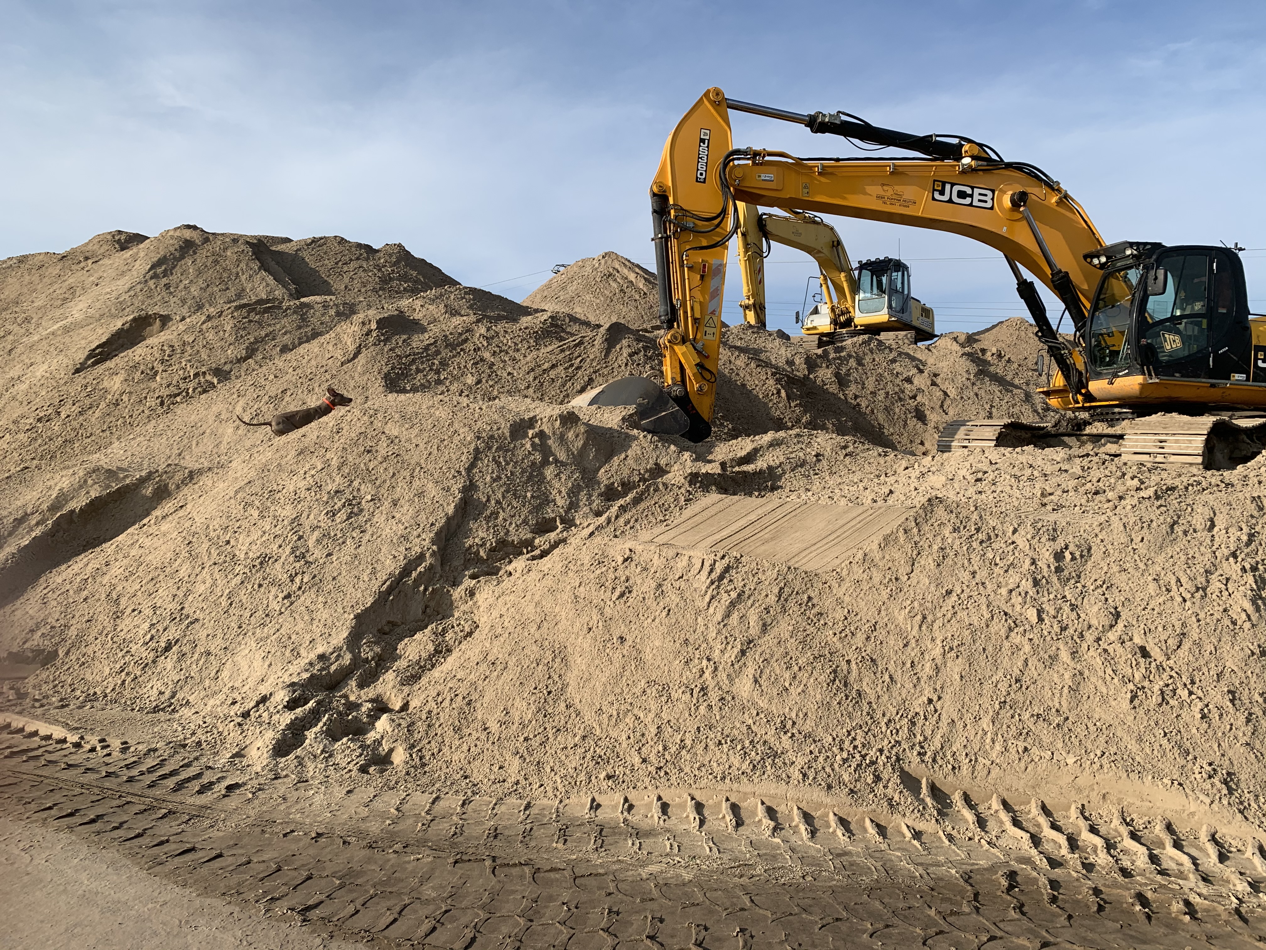 Graafmachines tussen heuvels zand en aarde op bouwterrein